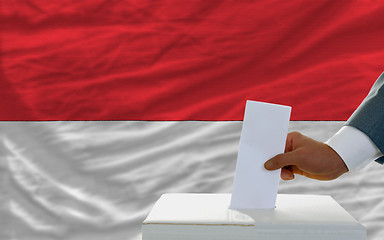 Image showing man voting on elections in indonesia in front of flag