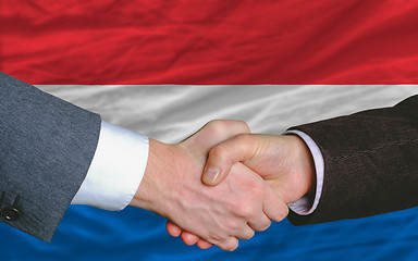 Image showing businessmen handshake after good deal in front of netherlands fl