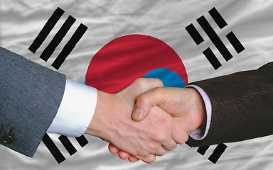 Image showing businessmen handshake after good deal in front of south korea fl