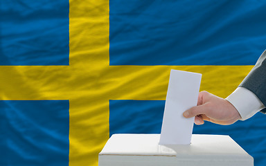 Image showing man voting on elections in sweden in front of flag