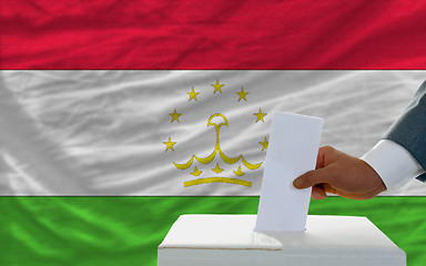 Image showing man voting on elections in tajikistan in front of flag
