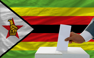 Image showing man voting on elections in zimbabwe in front of flag