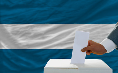 Image showing man voting on elections in el salvador in front of flag