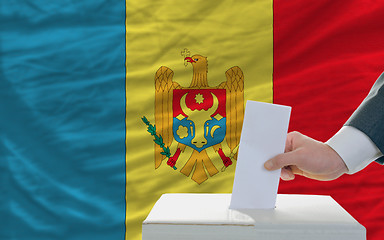 Image showing man voting on elections in moldova in front of flag