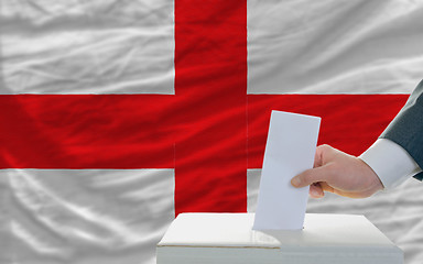 Image showing man voting on elections in england in front of flag