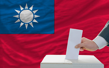 Image showing man voting on elections in taiwan in front of flag