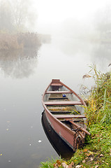 Image showing Wooden boat on coast of river sunken in dense fog.