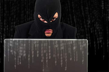 Image showing A hacker with a laptop against binary background
