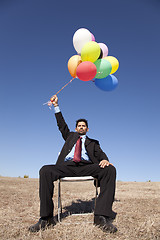 Image showing Businessman in outdoor holding balloons