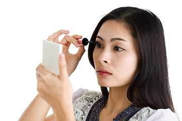 Image showing young woman putting on black mascara 