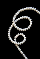 Image showing White pearls on the black silk as background 