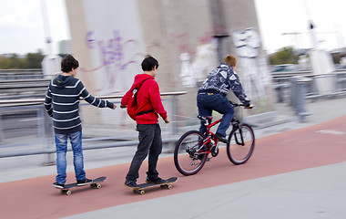 Image showing Teenagers ride bike and skateboard. Bicycle trail.