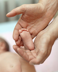 Image showing The little baby's legs in the hands of the big daddy