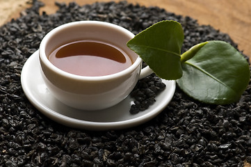 Image showing A cup of green tea with freh leaves