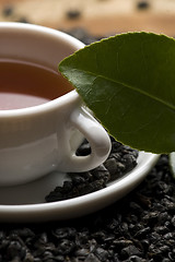 Image showing A cup of green tea with freh leaves