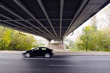 Image showing Bridge underneath over river and  car going fast.