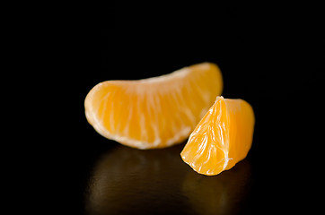 Image showing Close up of a juicy Clementine orange slice on a black background.