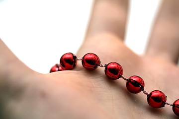 Image showing hand with red pearls