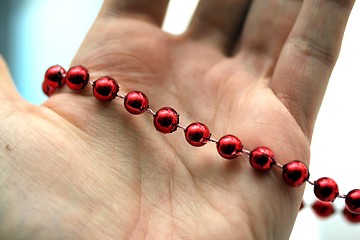 Image showing hand with red pearls