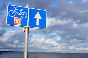 Image showing Bicycle path sign nr ten near lake and cloudy sky.