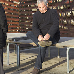 Image showing Elderly man tying shoes.