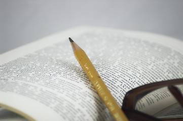 Image showing Pencil and glasses on a book