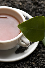 Image showing A cup of green tea with freh leaves