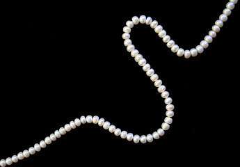 Image showing White pearls on the black silk as background 