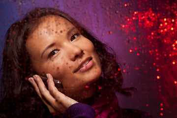 Image showing Asian woman behind the glass in rainy weather calling