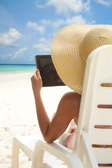 Image showing Woman sitting on the beach and browsing internet with tablet computer