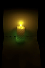 Image showing a burning candle on the background of an open notebook