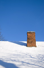 Image showing Snowy roof and red brick chimney