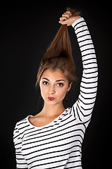 Image showing Beautiful girl in a striped dress pulls his hair