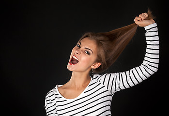 Image showing Beautiful girl in a striped dress pulls his hair