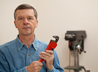 Image showing Senior man holding a large wrench