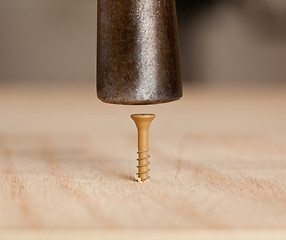 Image showing Screw being hit into wood by hammer