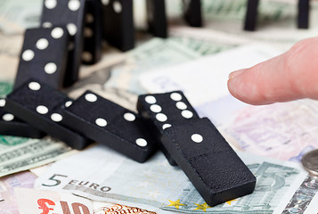 Image showing Finger on dominoes on bank notes