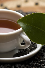 Image showing A cup of green tea with freh leaves