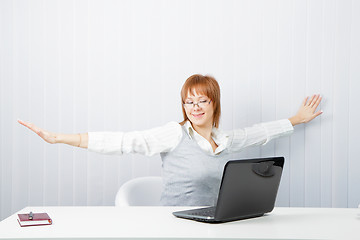 Image showing girl with a laptop stretches in the workplace