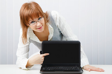 Image showing girl with glasses shows a finger on a laptop