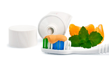 Image showing Toothbrush with orange toothpaste and orange slices