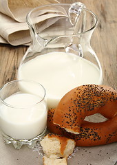 Image showing Bagel with poppy seeds, a pitcher of milk.