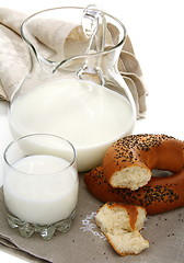 Image showing Bagel with poppy seeds a pitcher of milk.