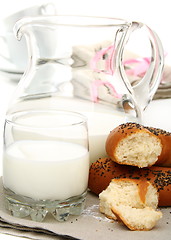 Image showing Bagel with poppy seeds a pitcher of milk.