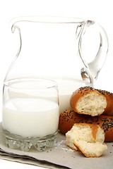 Image showing Bagel with poppy seeds a pitcher of milk.