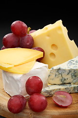 Image showing Cheese and grapes on a wooden board.