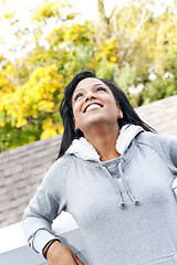 Image showing Smiling young woman outdoors looking up