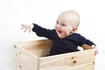 Image showing young child in wooden box pointing to the left