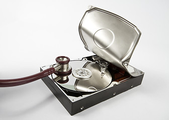 Image showing opened hard disk with stethoscope on grey background