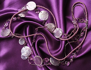 Image showing White pearls on a lilac silk as background 